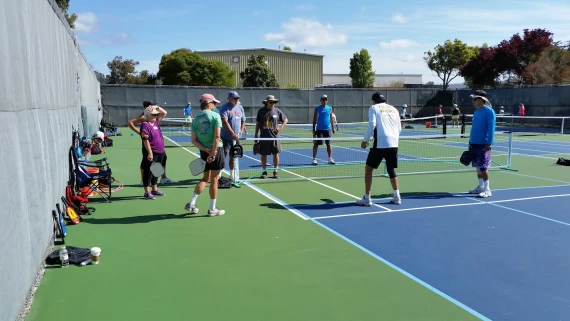 Group of pickleball players gathered on the Derby Park courts in Santa Cruz, preparing for a game.