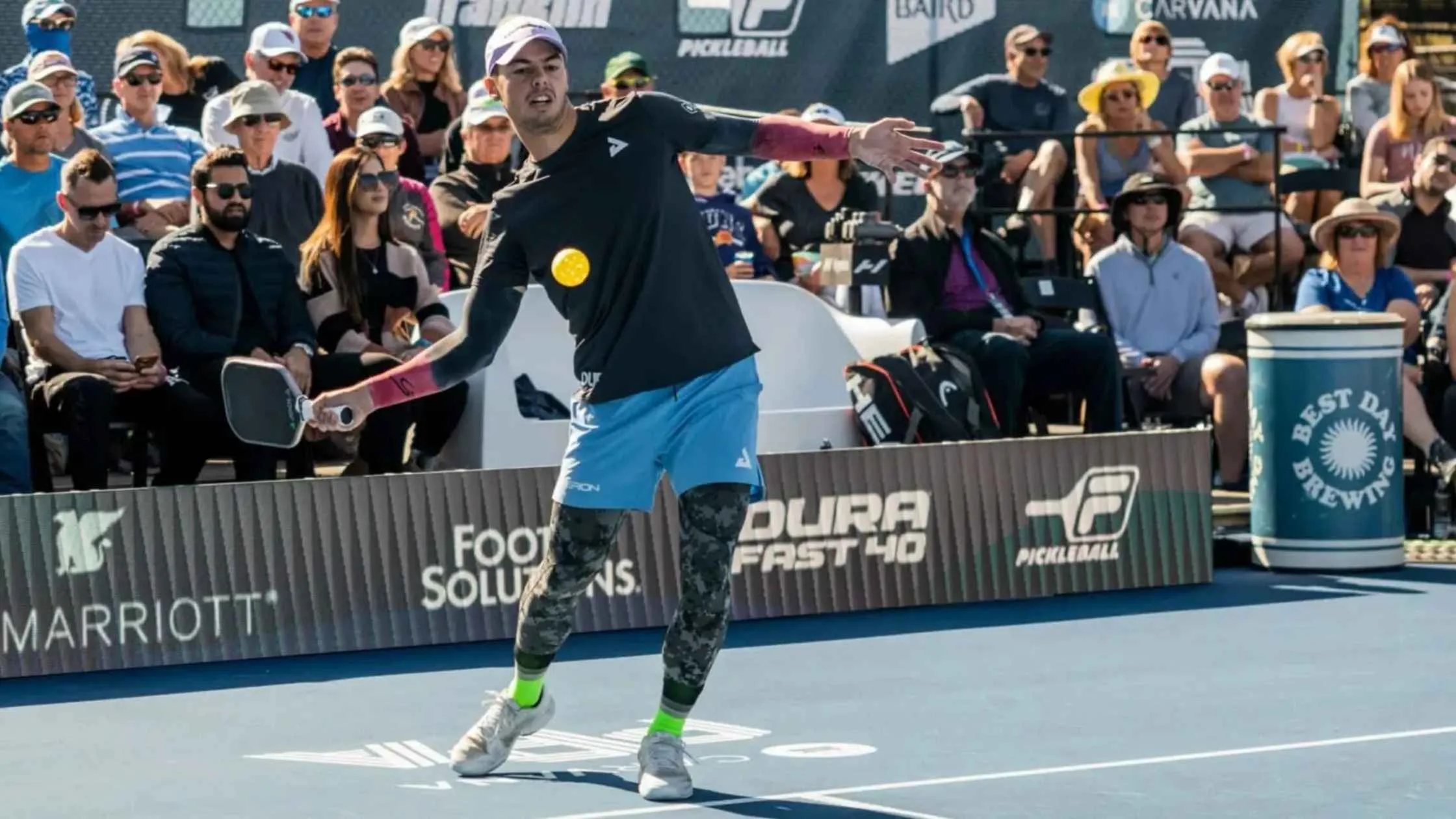Best professional pickleball player in action during a competitive match at a pro tournament with a crowd watching.