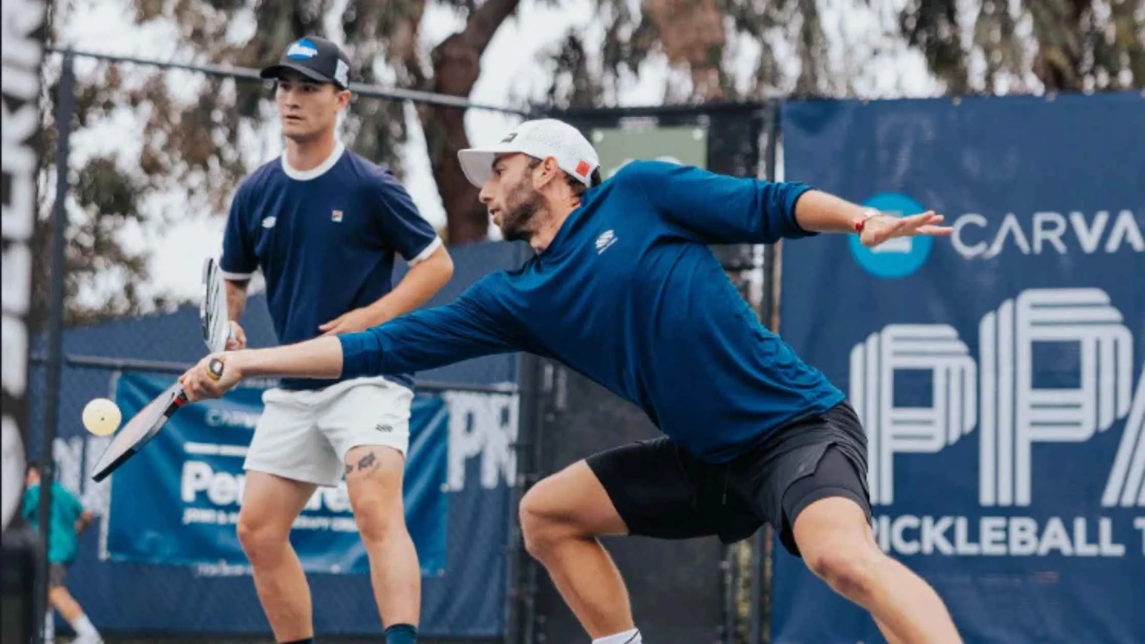 Two competitive athletes demonstrate pro pickleball tips during an intense doubles match on an outdoor pickleball court.